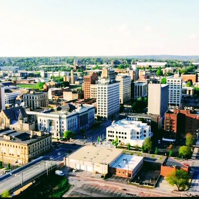 A bright aerial view of a mid-sized city's downtown with various buildings and greenery.