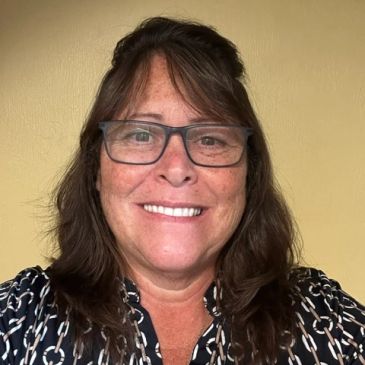 Smiling woman with glasses and brown hair.