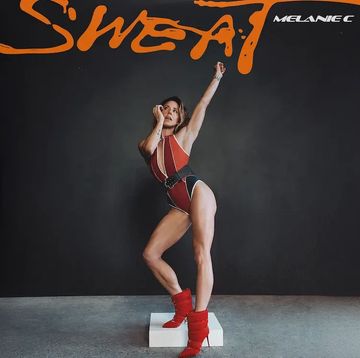 Melanie C poses dynamically in a red and black outfit against a dark background.