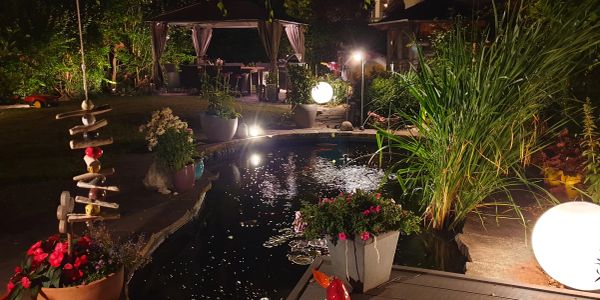 Abendliche Gartenbeleuchtung um einen Teich.