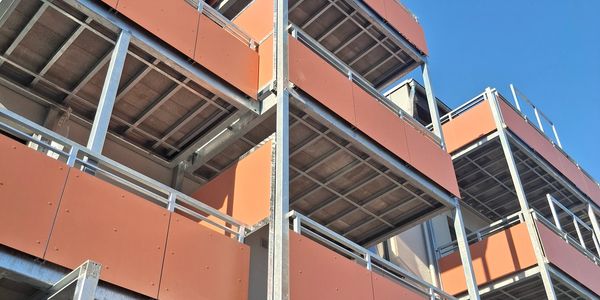 Eine moderne Gebäudefassade mit orangenen Paneelen gegen den blauen Himmel.