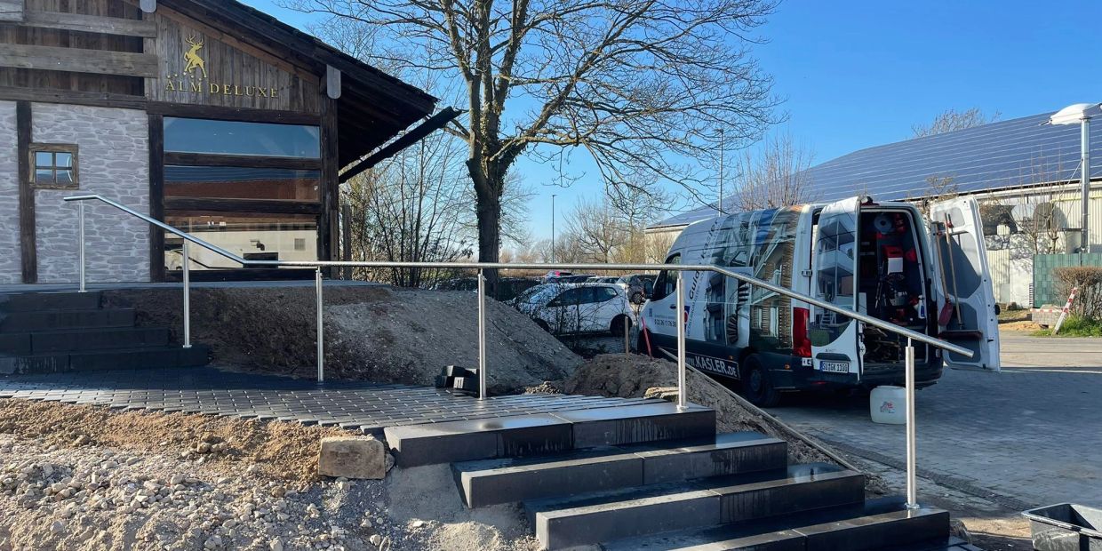 Treppenanlage mit Edelstahlgeländer vor einem modernen Gebäude.
