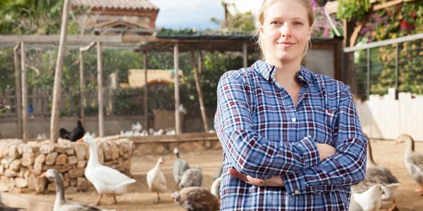 Young woman standing with farm birds outdoors.