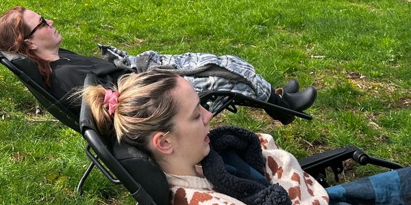 Two people relaxing on lawn chairs in the grass.