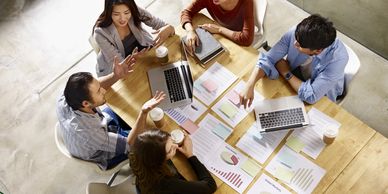 a strategic planning committee sitting at a table with laptops and reports