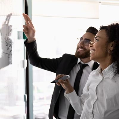 A consultant and her client writing ideas on a smartboard