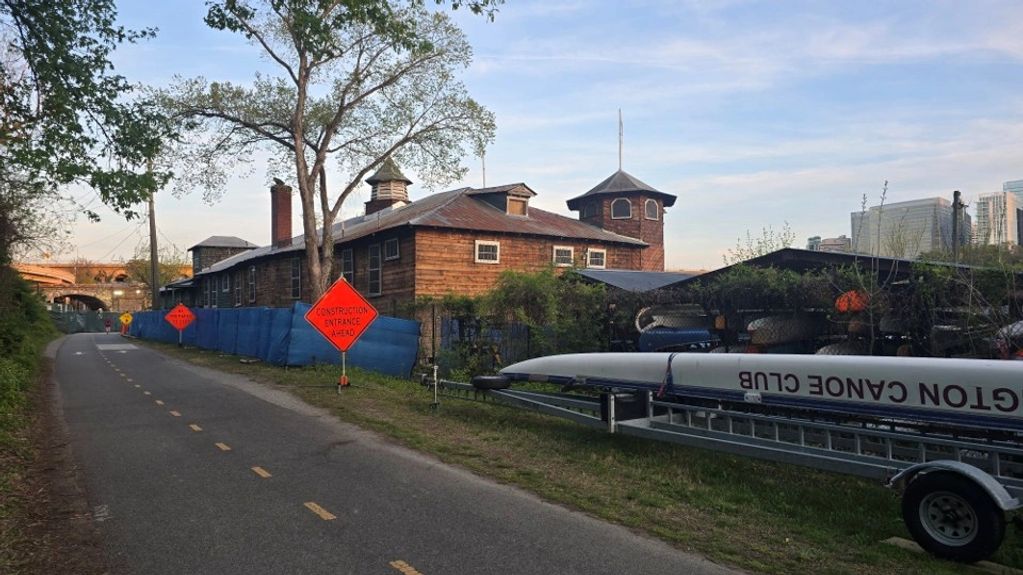 Historic wooden building and construction signs along a paved pathway.