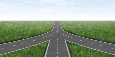 A three-way road intersection surrounded by grass.