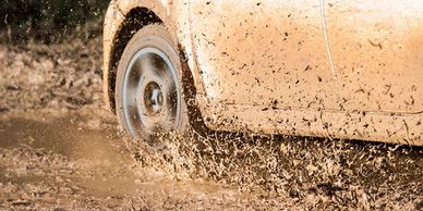 Car tire splashing mud on a muddy road.