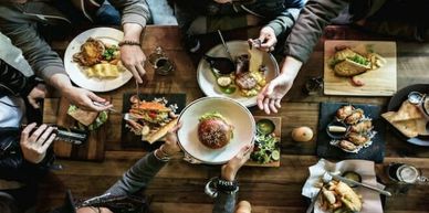 Friends sharing a meal at a wooden table.