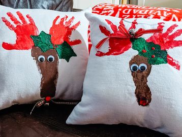 Festive reindeer pillows made with handprints and footprints.