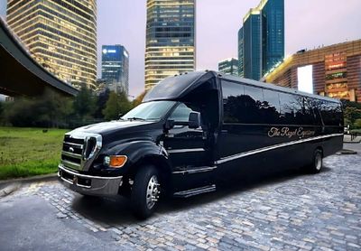 A sleek black luxury bus named The Royal Express parked on a cobblestone street.