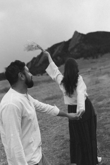 Couple holding hands in a scenic outdoor setting with mountains.