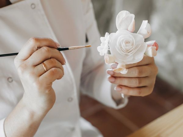 Confectioner's hands make decorations, sugar flowers for a wedding cake. 
