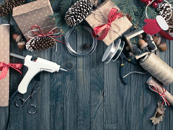 Christmas background. Packed gifts and scrolls, spruce branches and tools on shabby wooden table.