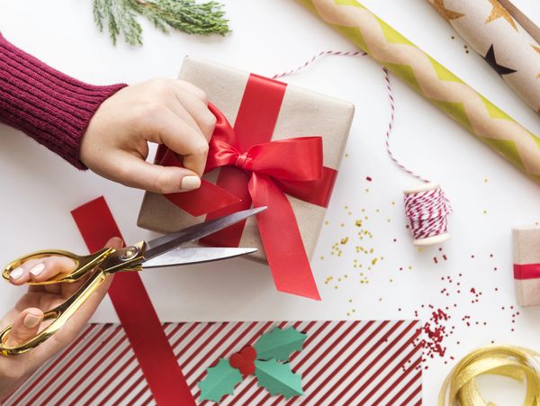 Woman s hands wrapping Christmas gift boxes, close up.
