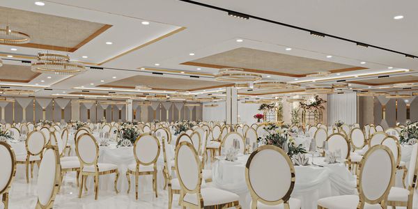 Elegant banquet hall with white and gold chairs and round tables.