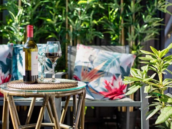 Bottle of red wine and glasses on table in a cozy outdoor setting.