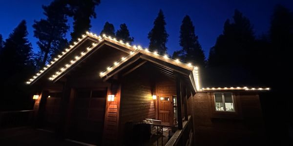 Cozy cabin lit with string lights against a deep blue night sky.
