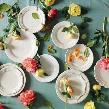 Elegant white plates arranged with colorful flowers on a teal background.