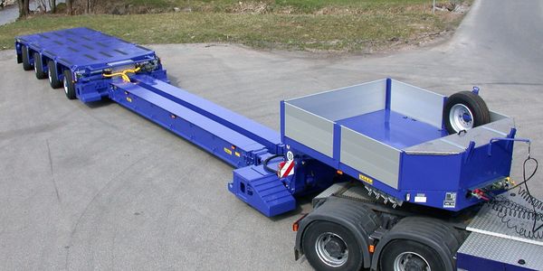 Blue heavy-duty extendable flatbed trailer attached to truck.