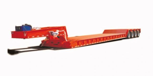Red lowboy trailer with multiple axles for heavy hauling.