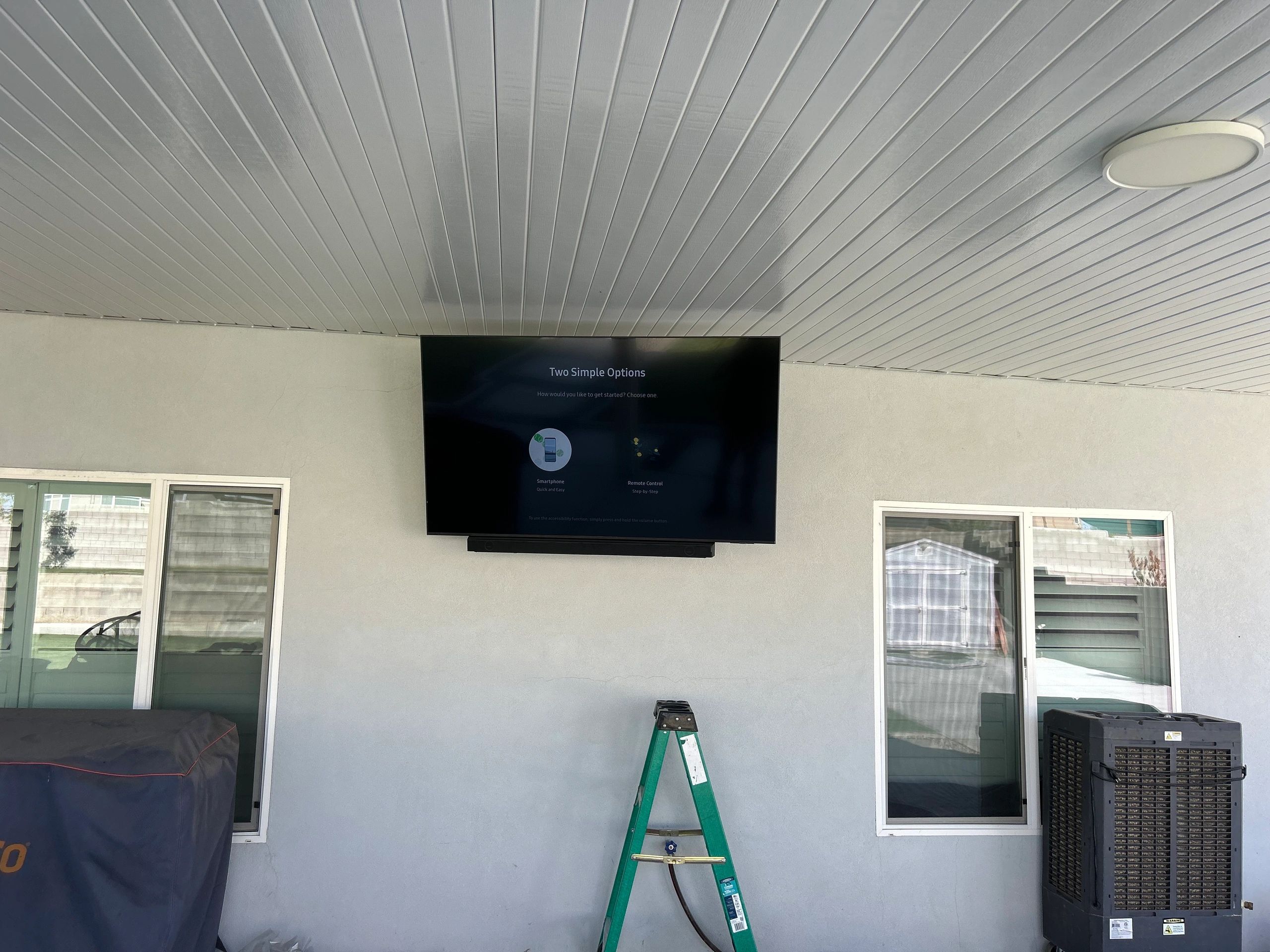 TV mounted on a wall with a step ladder below.