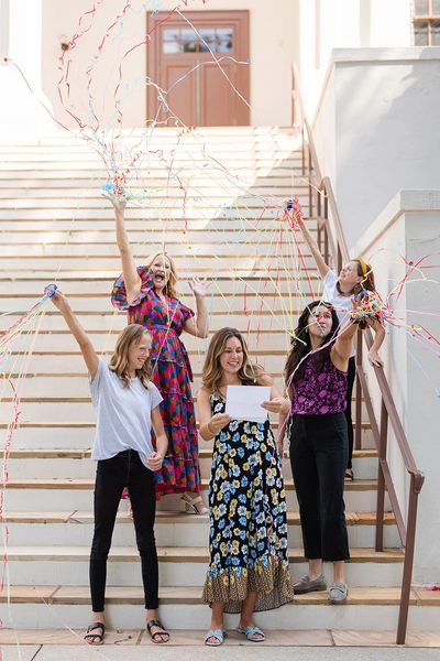 Four women celebrating with streamers on stairs.