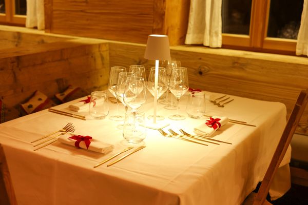 Elegant dining table set with glassware and napkins tied with red ribbons.