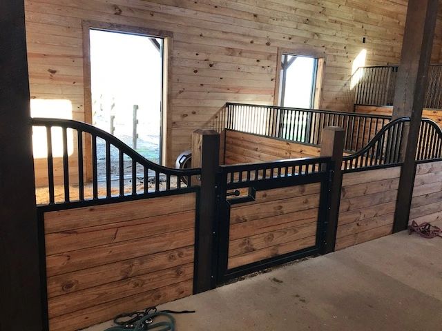Interior view of a wooden horse stable with metal railings.