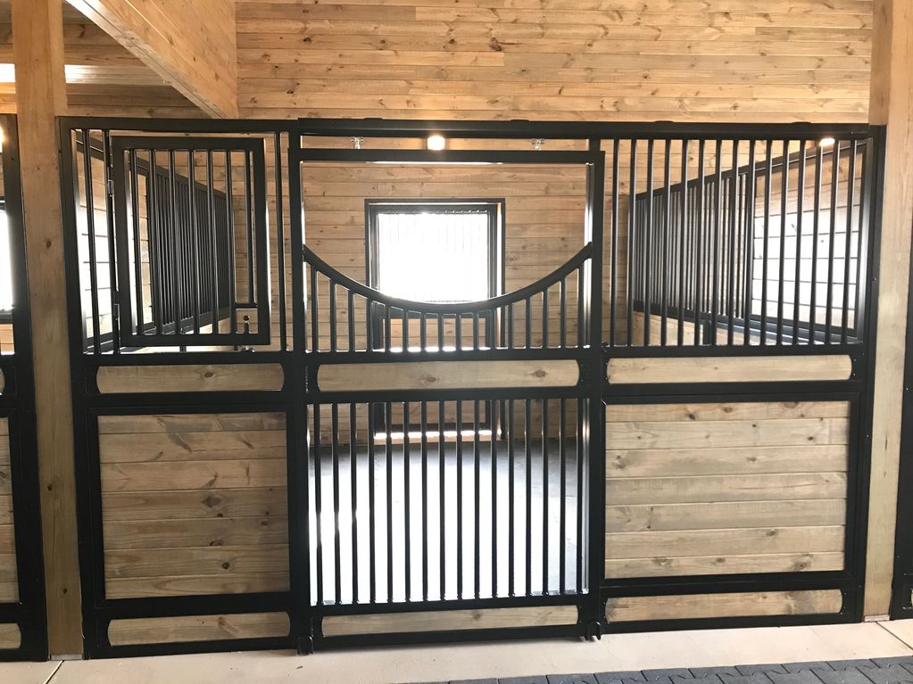 Black metal and wood stable gate inside a wooden barn.