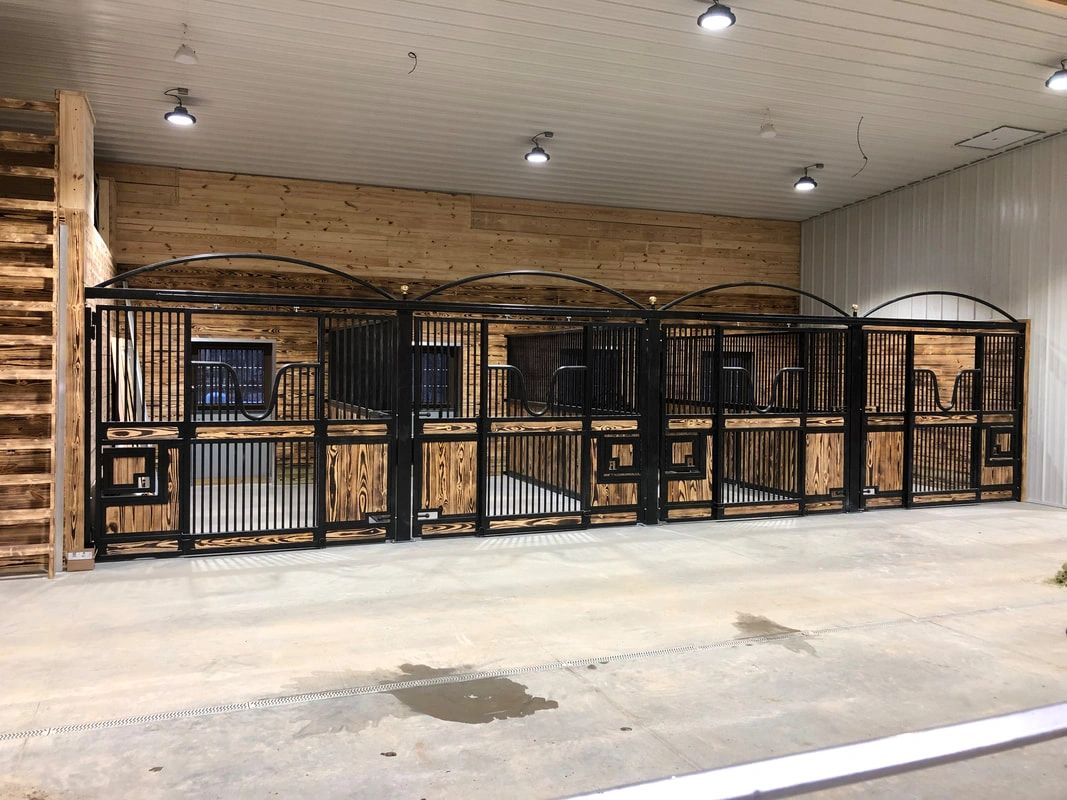 Indoor horse stalls with black and wood design.