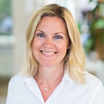 Smiling woman with blonde hair in a white shirt.