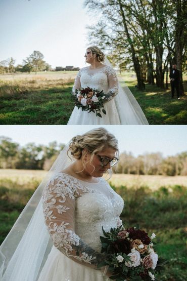 Bride in lace wedding dress holding bouquet in outdoor setting.