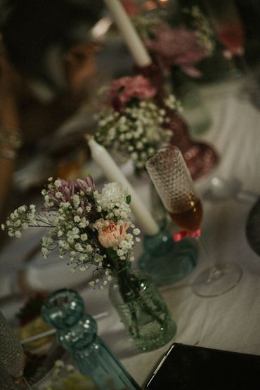 Elegant table setting with flowers, candles, and a glass of drink.