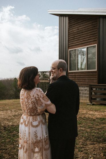 Couple sharing a tender moment outside a rustic house.