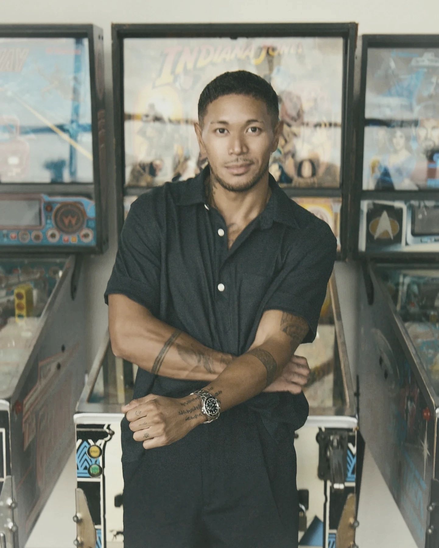 Man posing in front of vintage arcade machines.