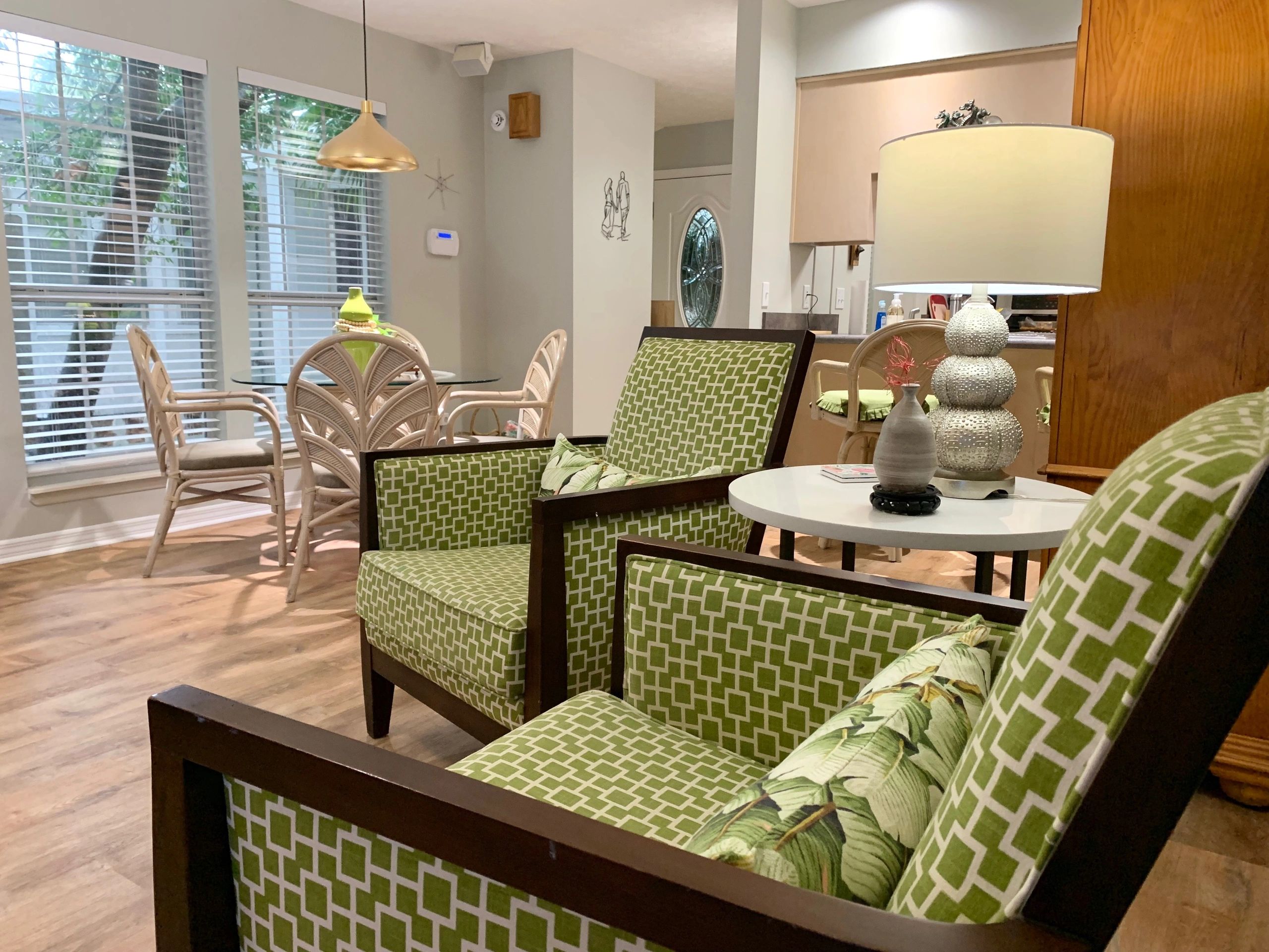 Cozy living space with green-patterned chairs and a round dining table by the window.