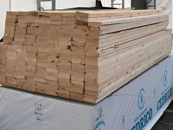 Stack of 2x6 lumber boards stored inside a covered metal-frame shelter.