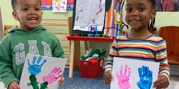 Two children showing handprint art happily.
