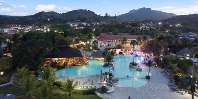 A scenic resort with a large pool and mountainous backdrop at dusk.