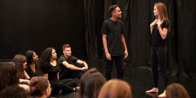 Young actors rehearsing a scene in a theater.