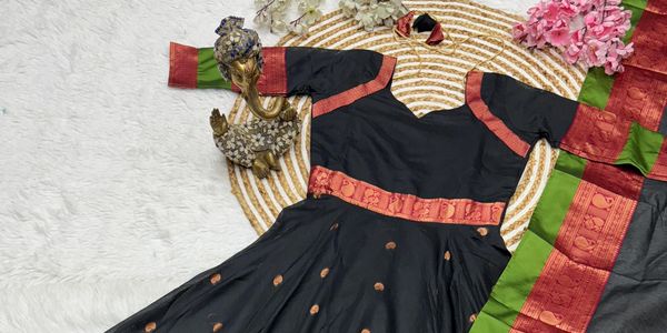 Black traditional dress with red and green silk borders and golden motifs.