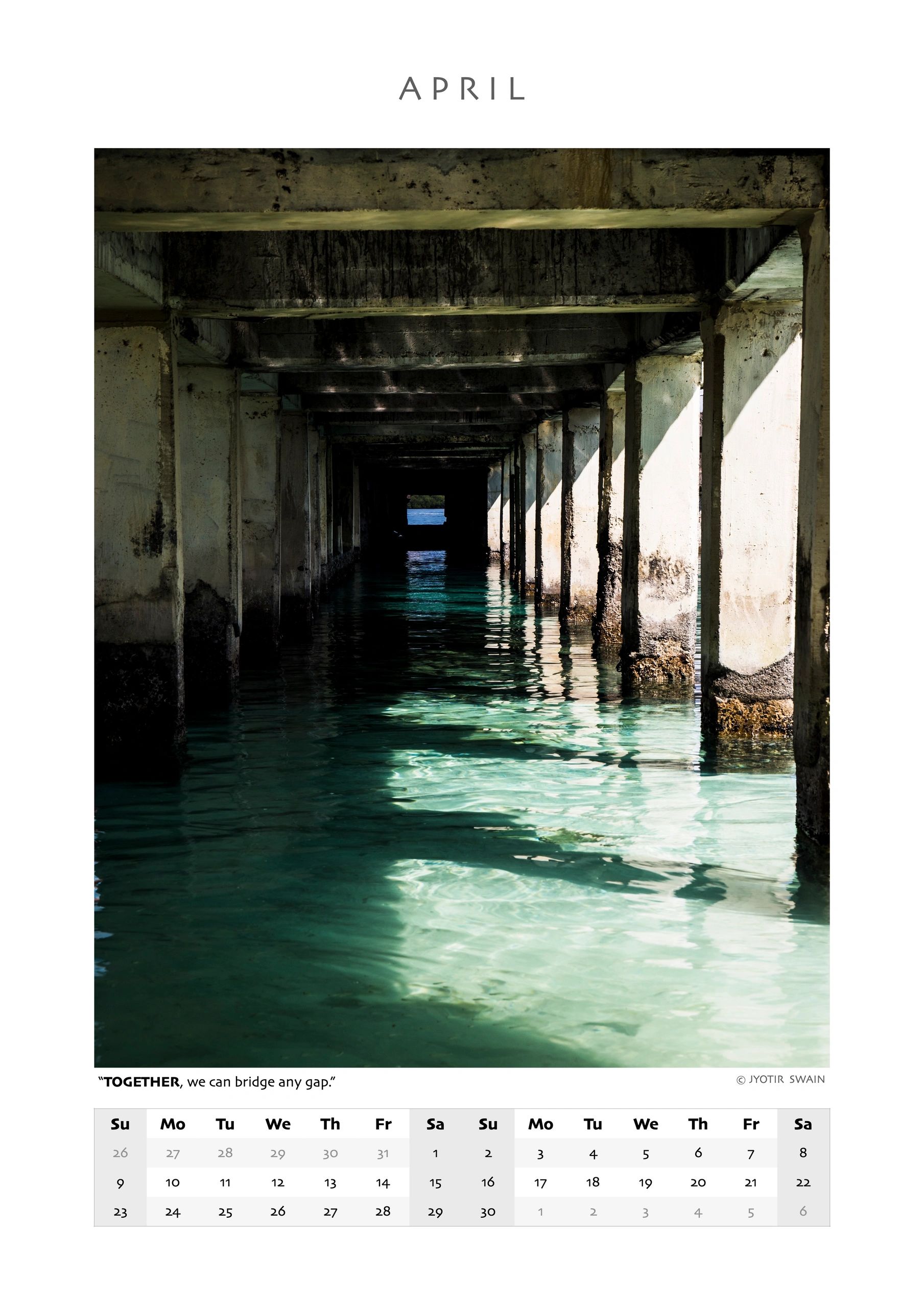 Sunlight filters through pillars over clear water beneath a bridge.