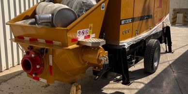 Industrial concrete pump machine parked outdoors near a building.