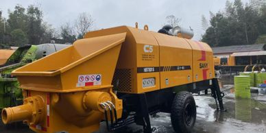 Large yellow industrial concrete pump machine outdoors.