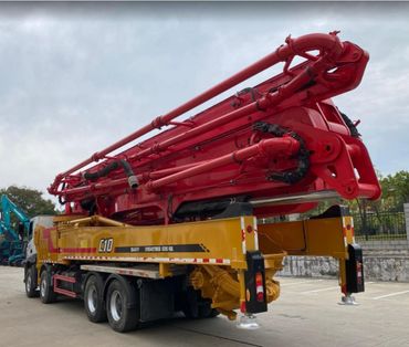 A large yellow and red concrete pump truck parked outdoors.