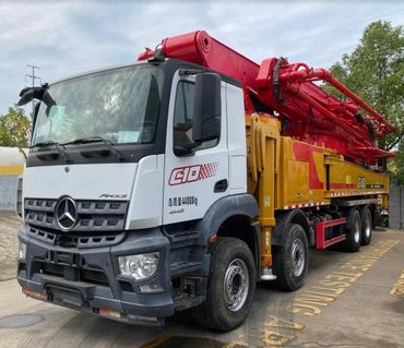A large red and yellow concrete pump truck parked outdoors.