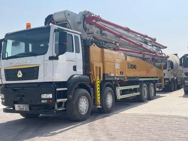 Large concrete pump truck parked outdoors under clear sky.
