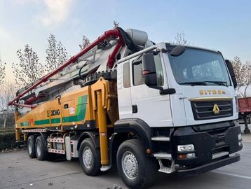 A large concrete pump truck parked outside with extended boom arm.